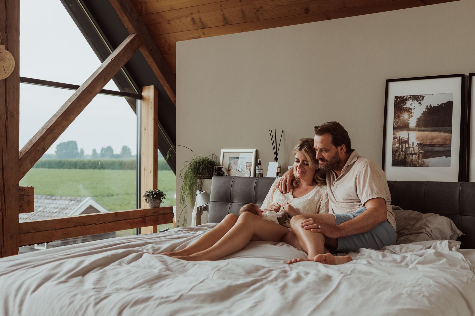 Een man en een vrouw zitten op een bed en kijken naar een tablet.