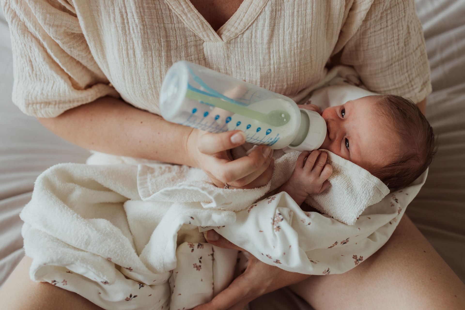 Een vrouw voedt haar baby uit een flesje.
