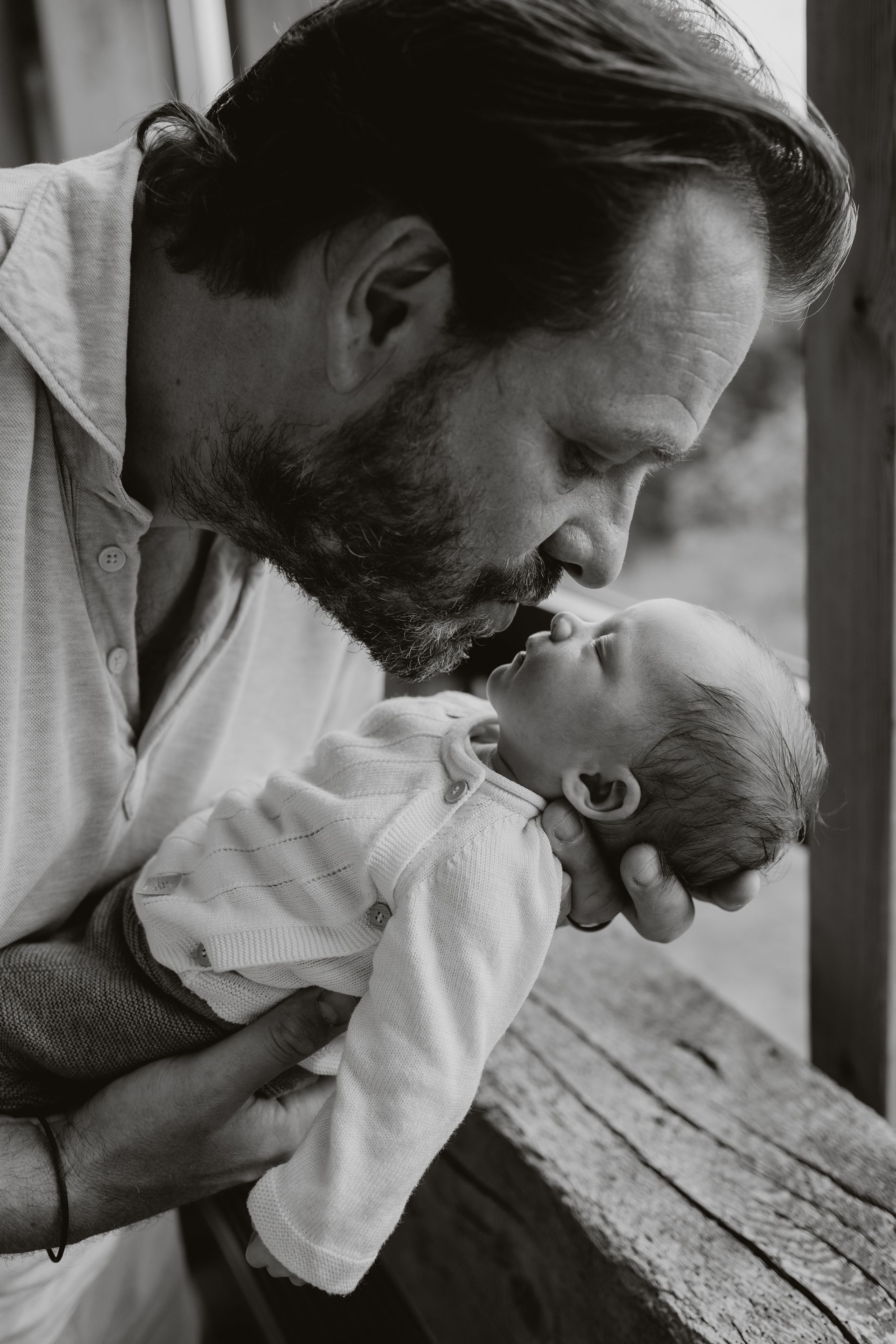 Een zwart-witfoto van een vader die zijn baby vasthoudt.