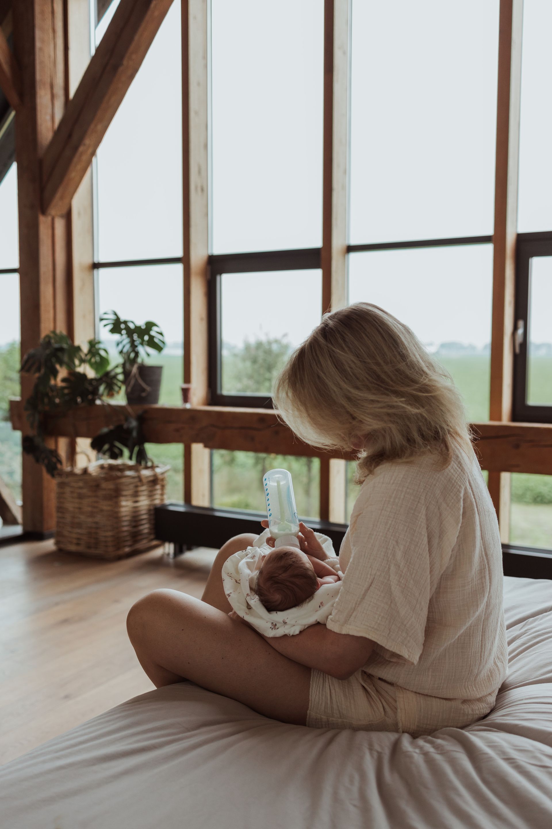 Een vrouw zit op een bed met een baby in haar armen.