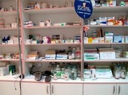 Una fila de estantes llenos de muchos medicamentos en una farmacia.