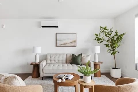 Bright open-plan living room with leather chairs, rug, dining area, and kitchen in the background