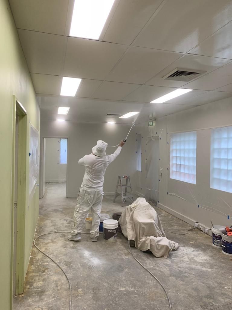 A man is painting the ceiling of a room.