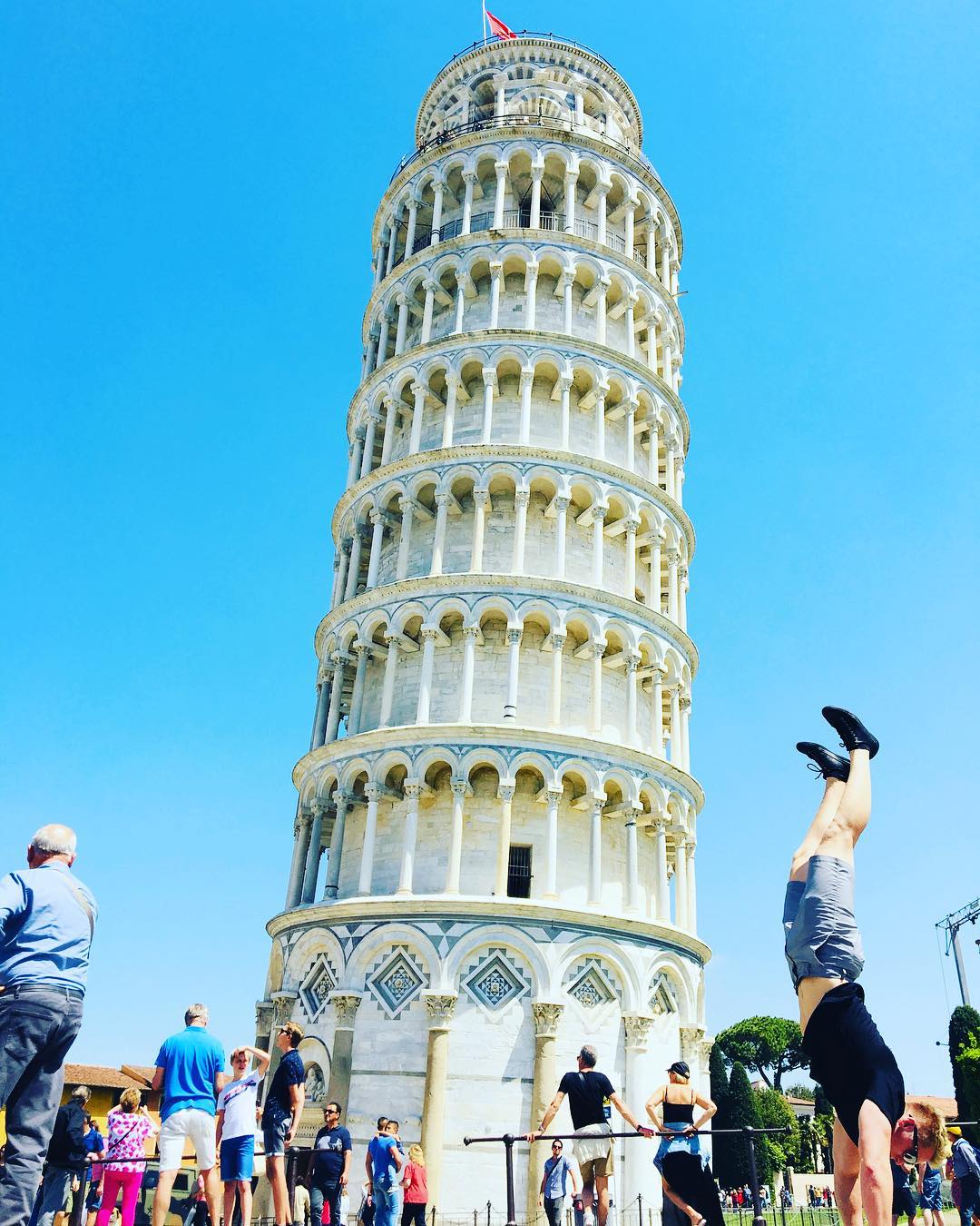 Xander Clemens performing a handstand in front of the Leaning Tower of Pisa in Pisa, Italy.