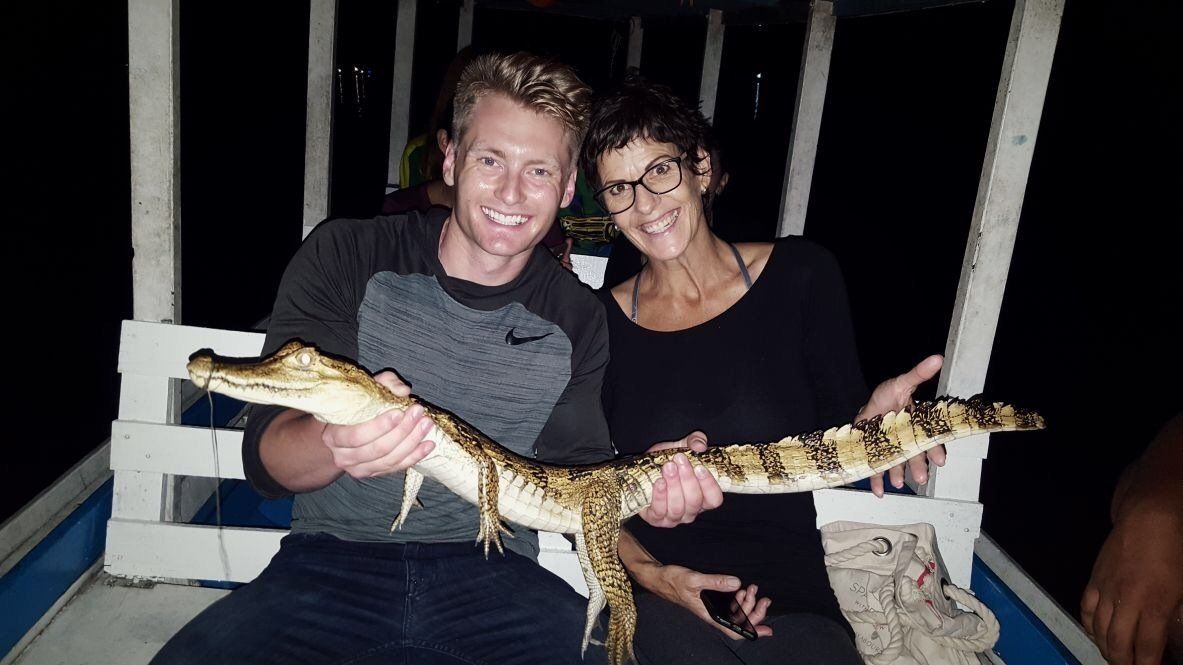 Xander Clemens with Sonja van Wyk in the Amazon River holding a caiman.