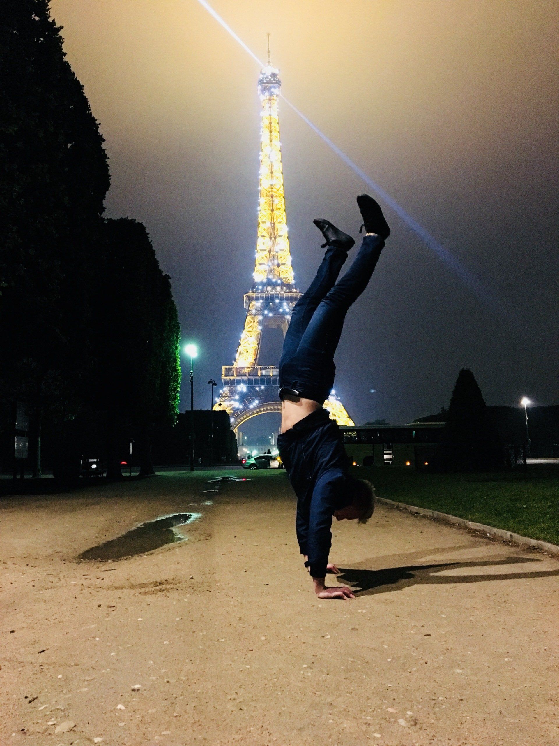 Xander Clemens performing a handstand in front of the Eiffel Tower in Paris, France