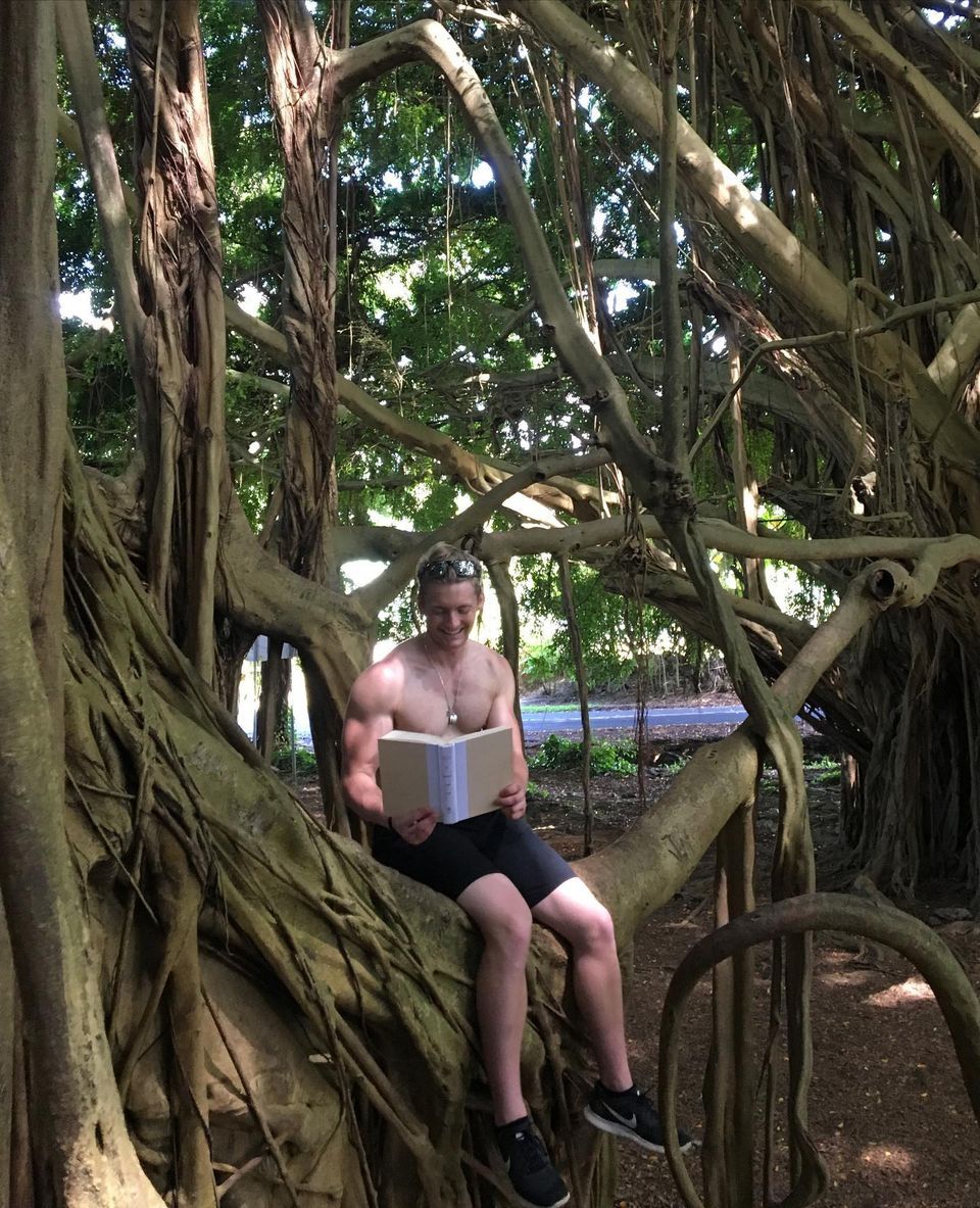 Xander Clemens at Rainbow Falls, Hawaii reading the book 12 Rules For Life An Antidote to Chaosβ by Jordan B Peterson