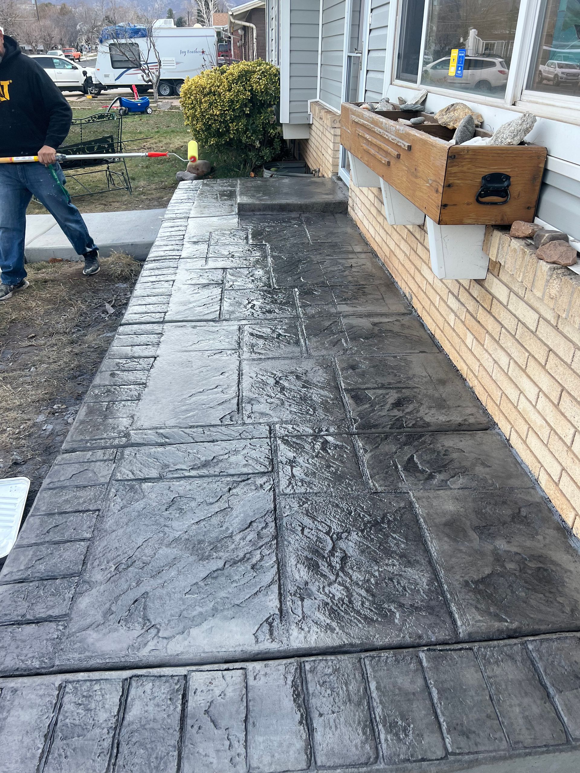 A man is sweeping the sidewalk in front of a house.