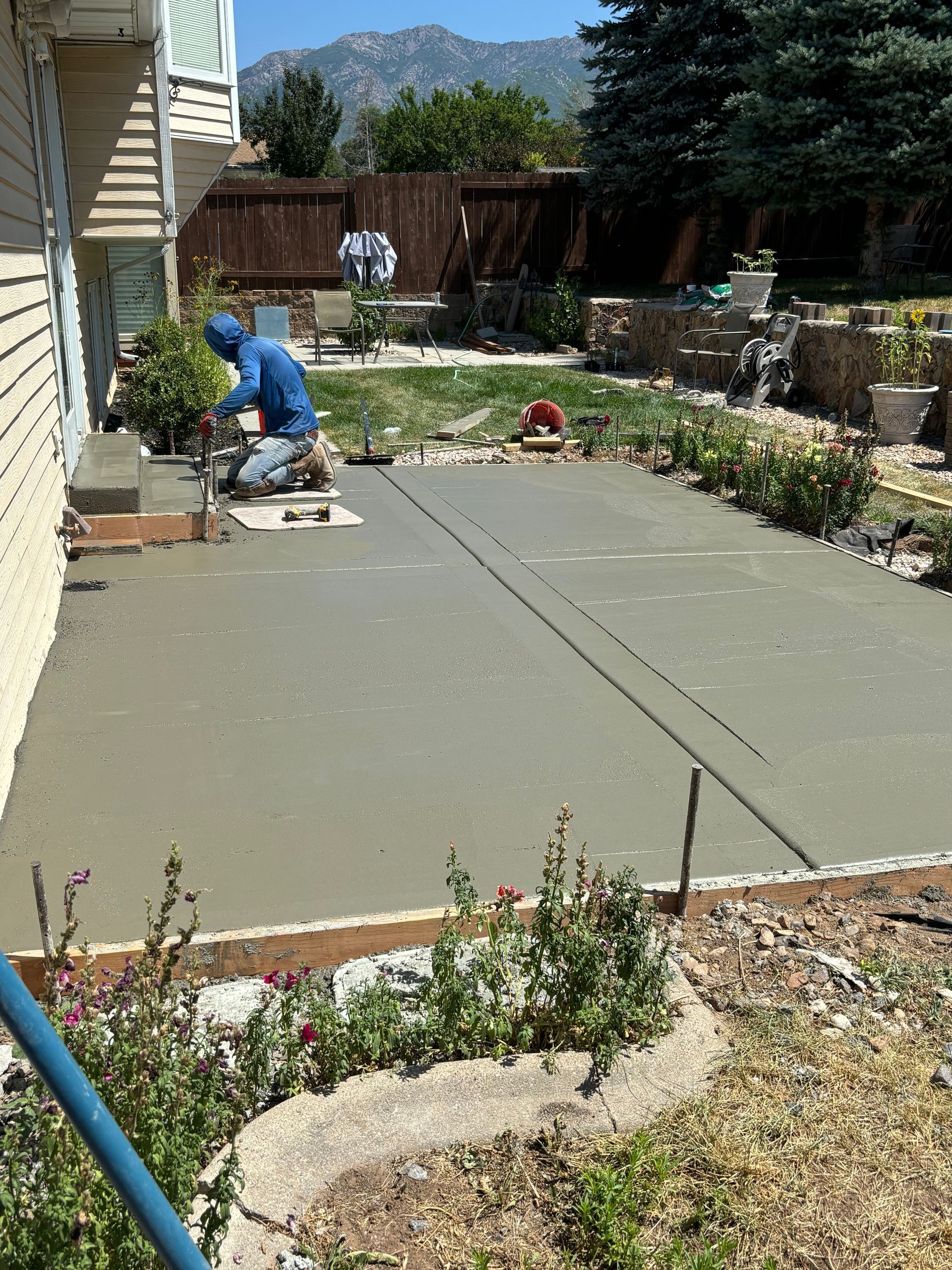 A man is working on a concrete patio in front of a house