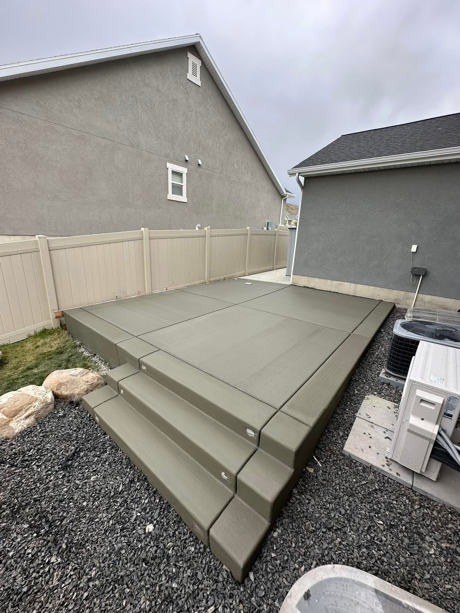 A concrete deck with stairs and a fence in front of a house.