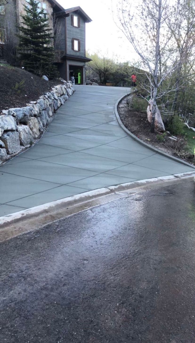 A concrete driveway leading to a house on a hill.
