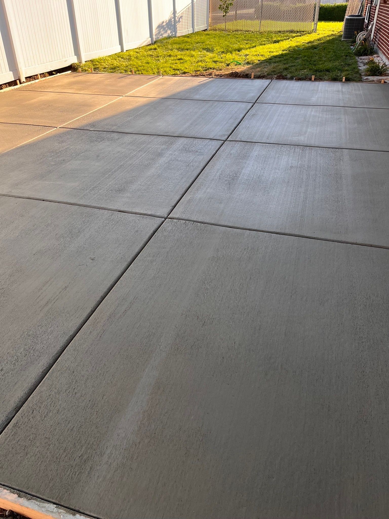 A concrete driveway is being built in the backyard of a house.