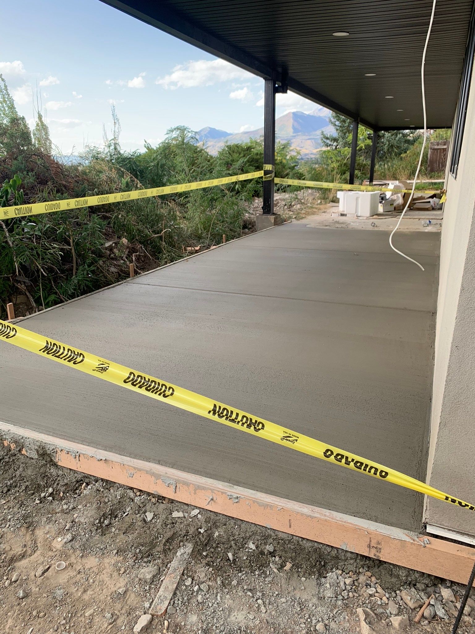 A concrete porch is being built with yellow tape around it.