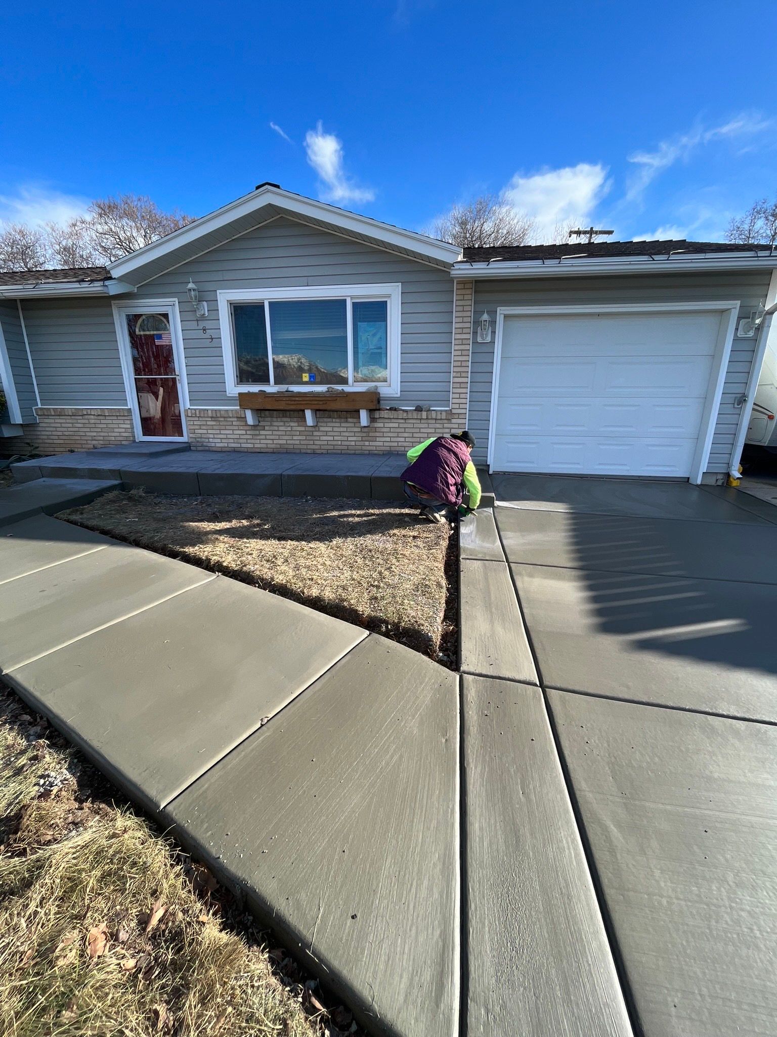 A person is working on the sidewalk in front of a house.