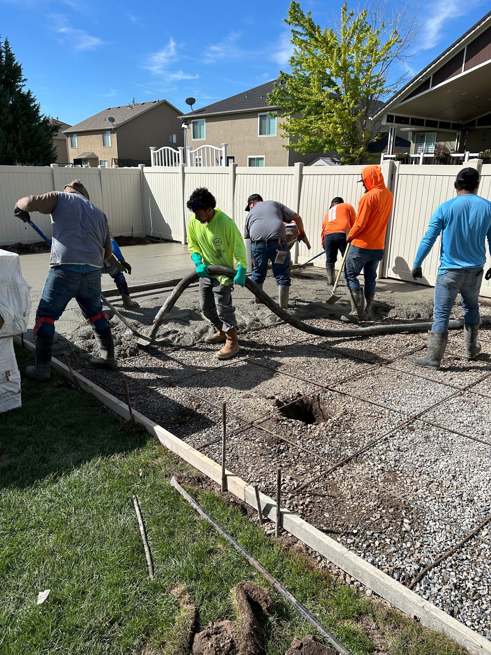 A group of men are working on a concrete driveway.