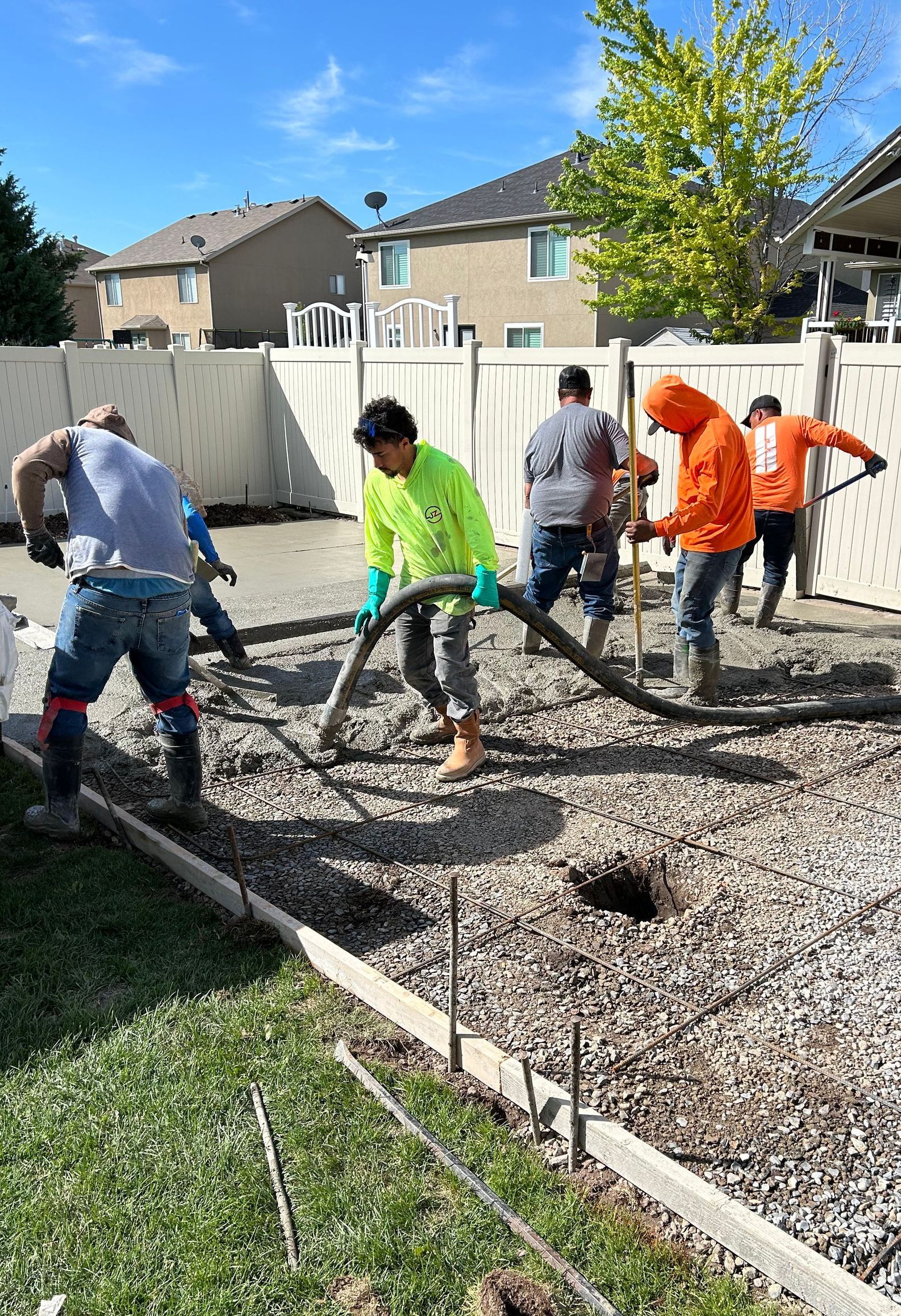 A group of construction workers are working on a concrete driveway.