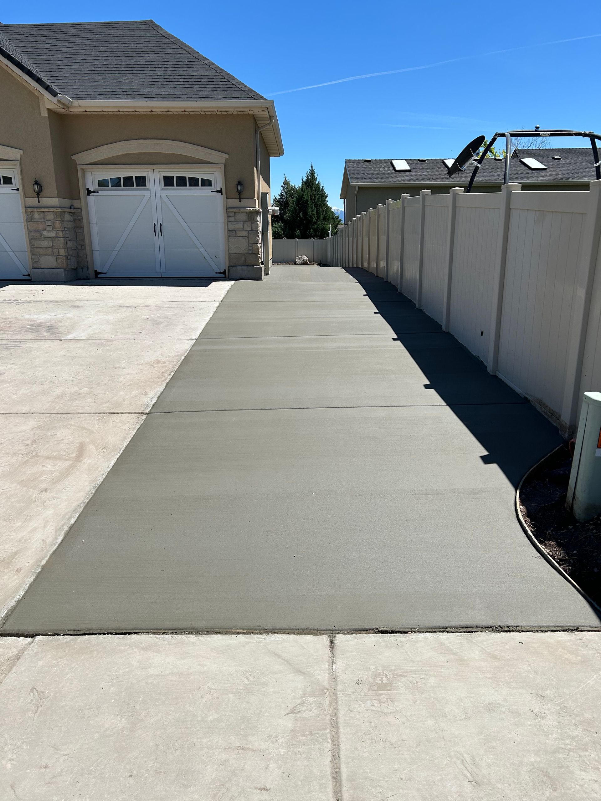 A concrete driveway leading to a house with two garage doors