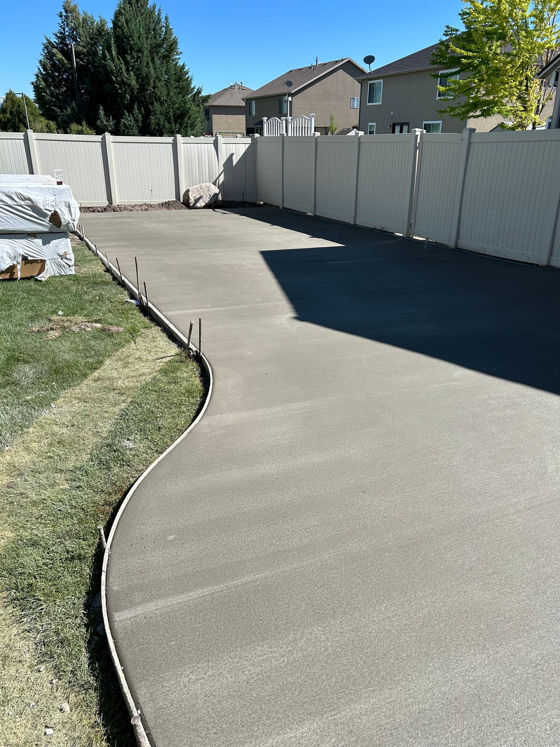 A concrete driveway with a white fence in the background