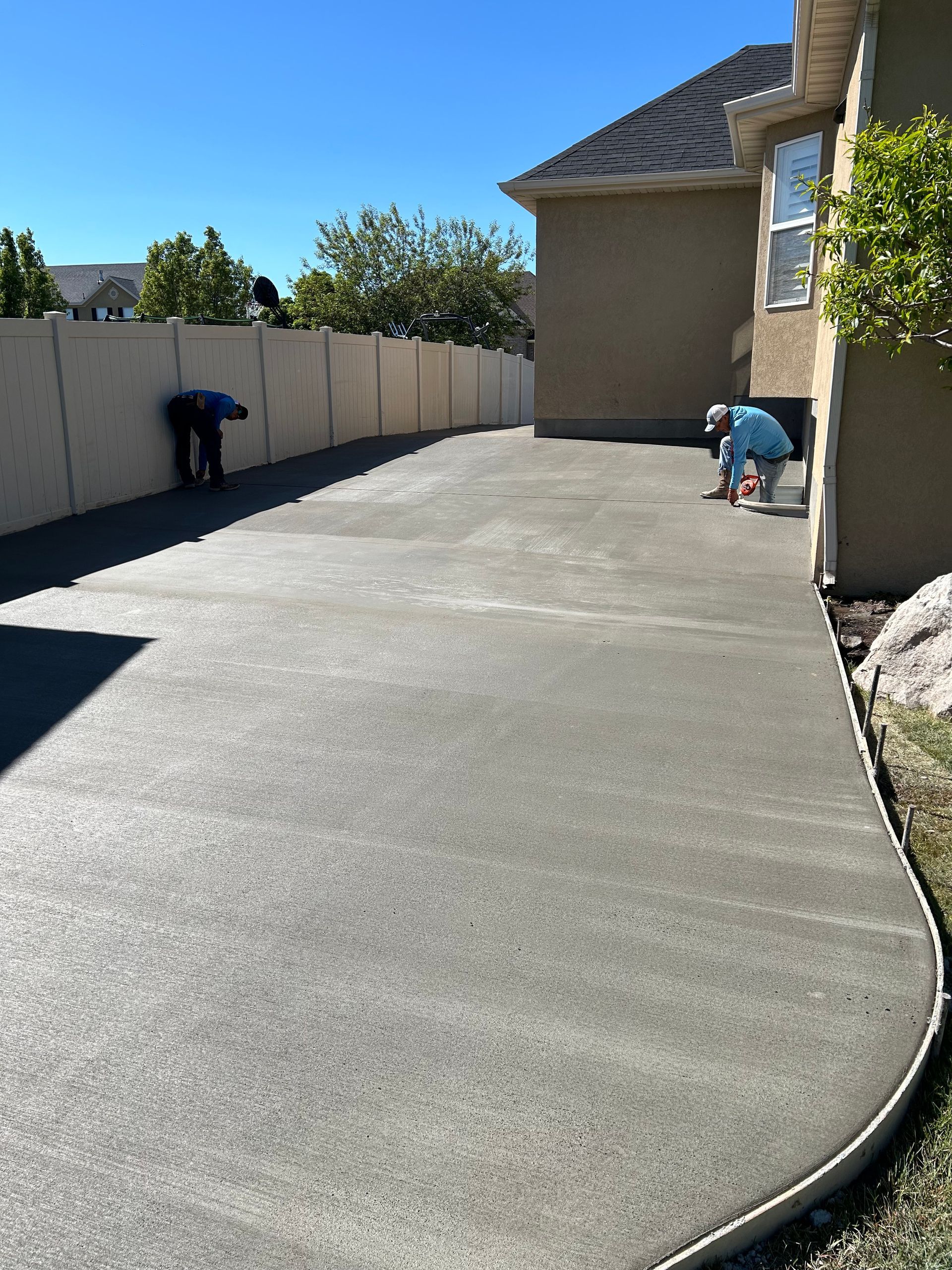 A man is working on a concrete driveway in front of a house