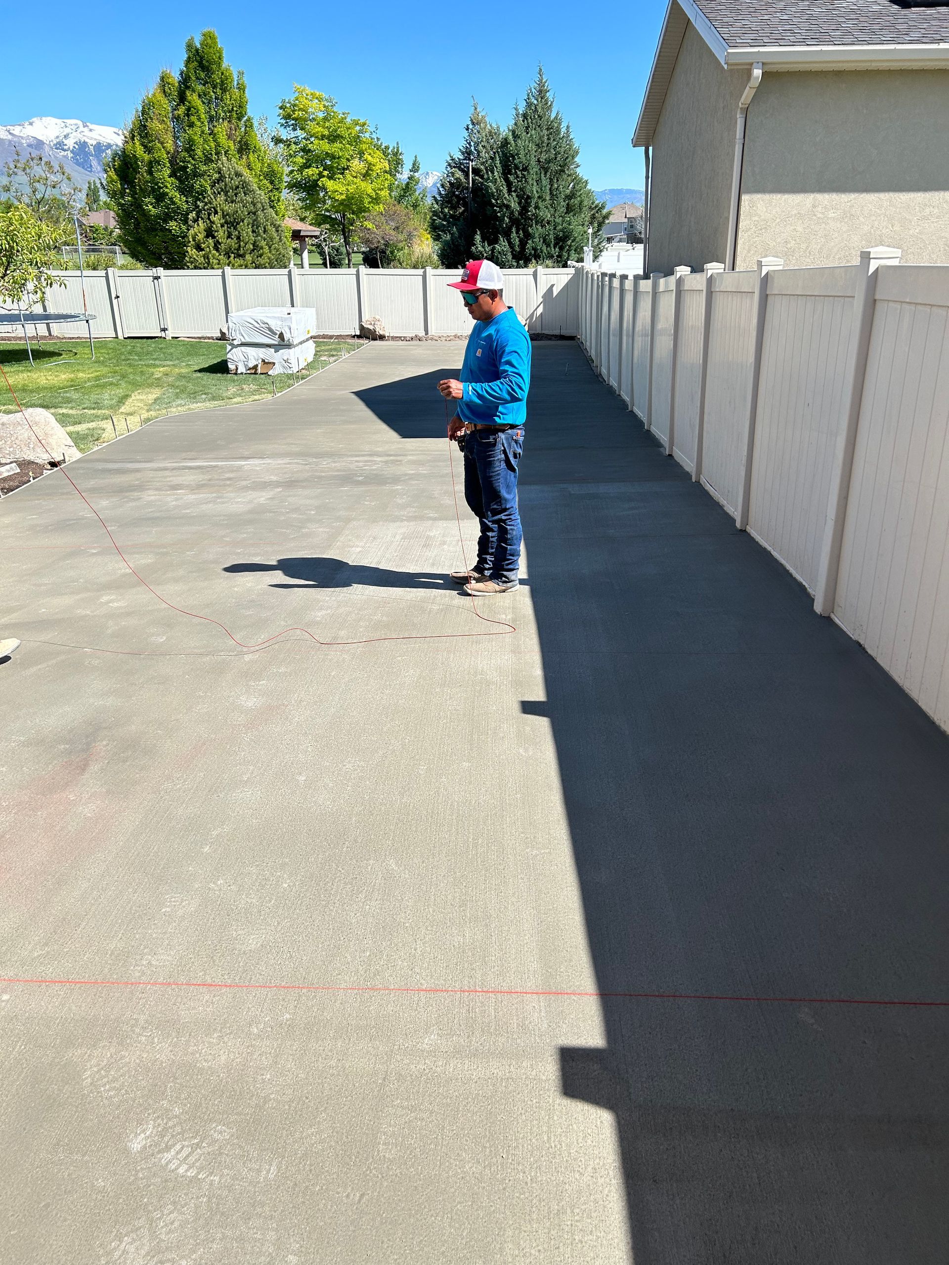 A man is standing on a sidewalk next to a white fence.