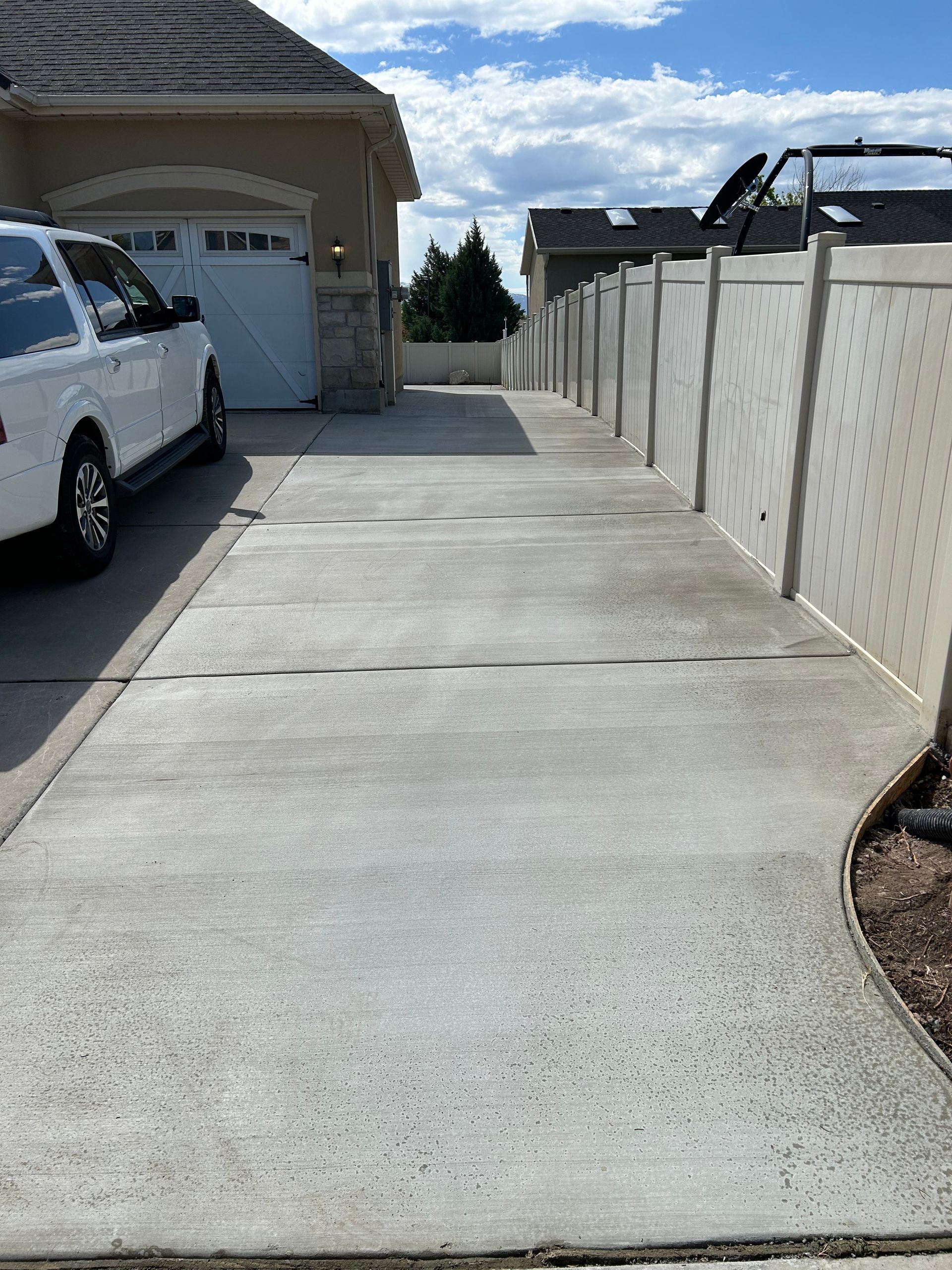 A white truck is parked in a driveway next to a house.
