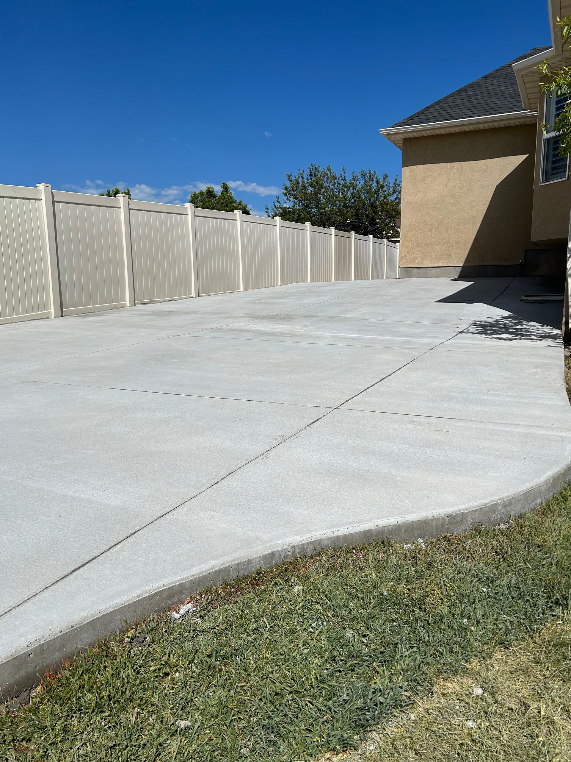 A concrete driveway with a fence and a house in the background
