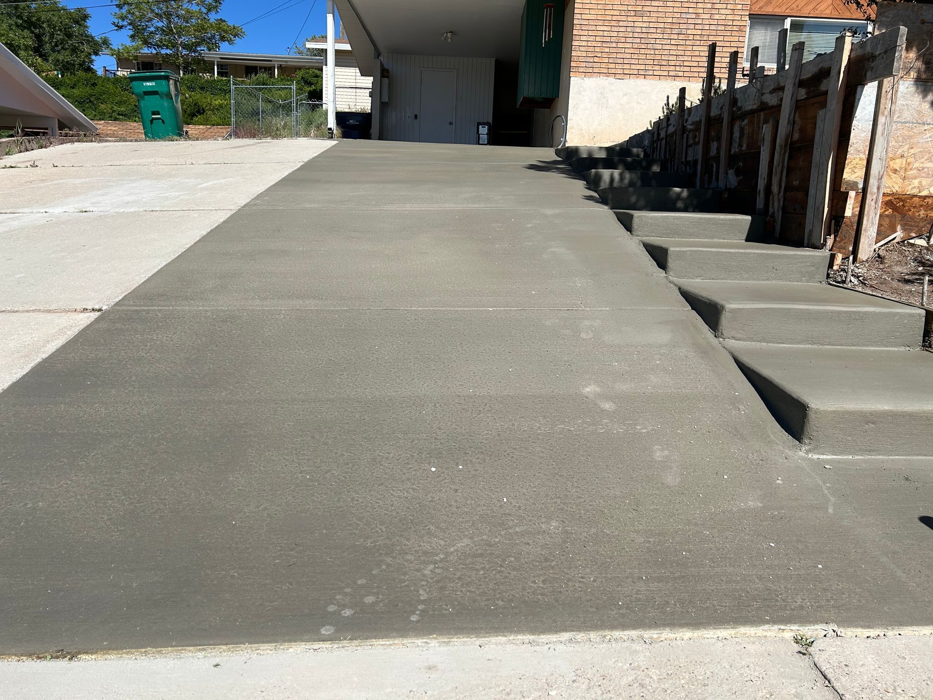 A concrete driveway with stairs leading up to a house.