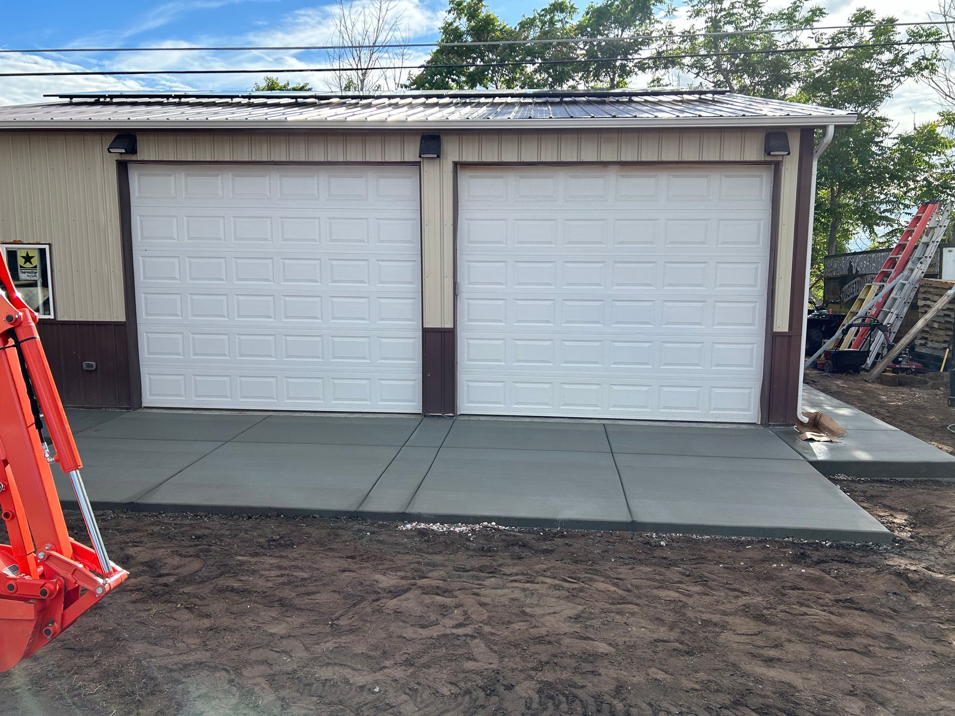 A garage with two white garage doors and a concrete driveway