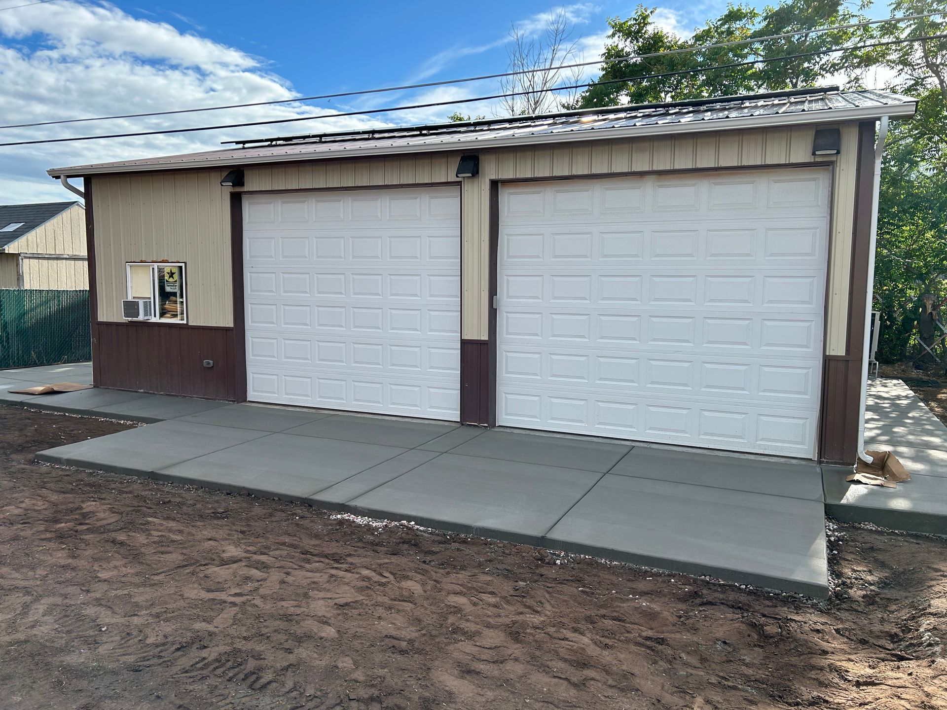 A garage with two white garage doors and a concrete walkway.