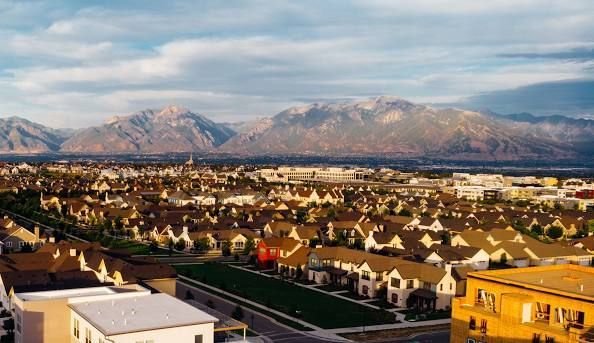 A sunset over a lake with trees in the foreground and a bridge in the background.