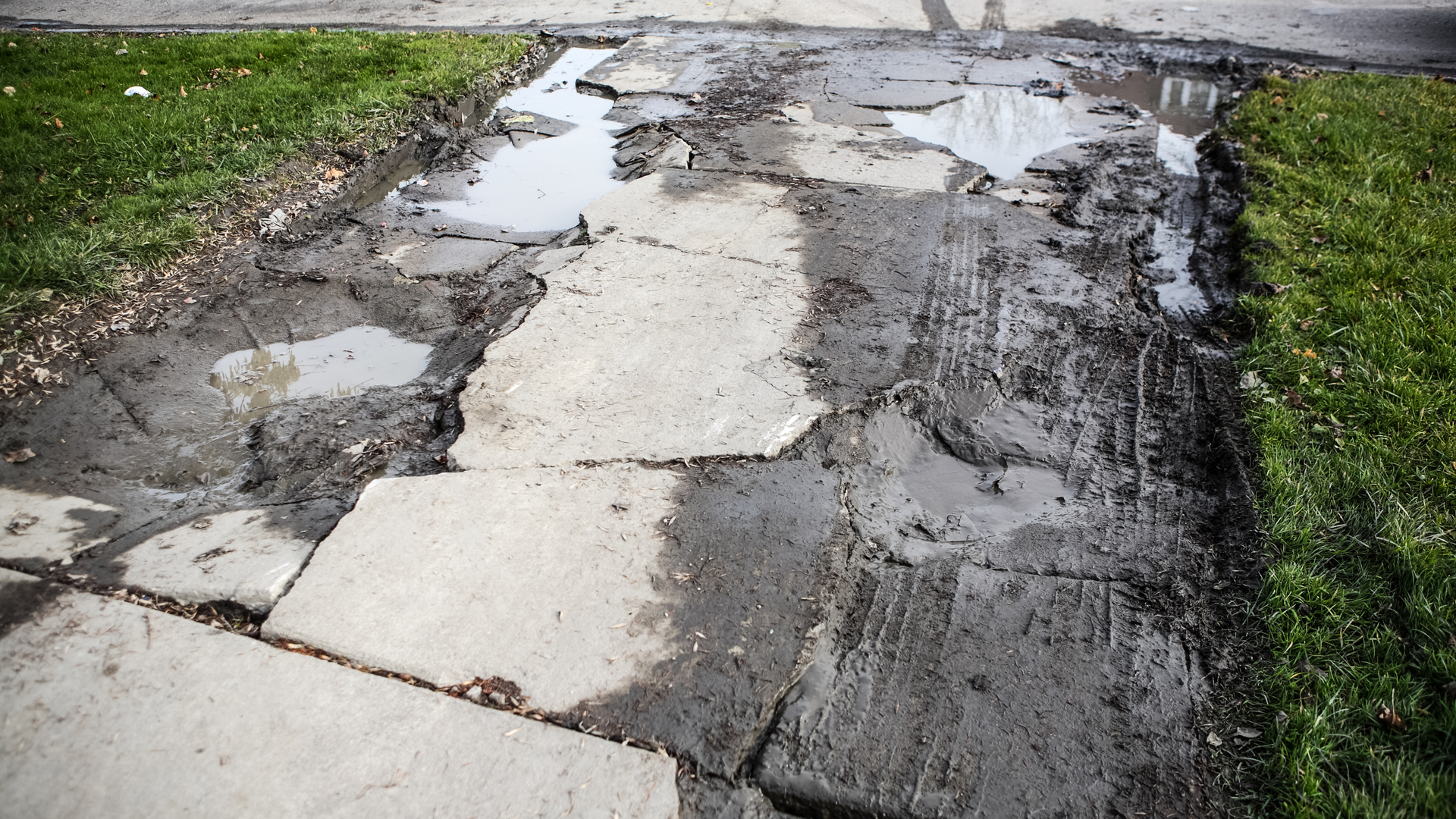 Concrete driveway damage caused by freeze thaw cycles showing cracks and surface wear