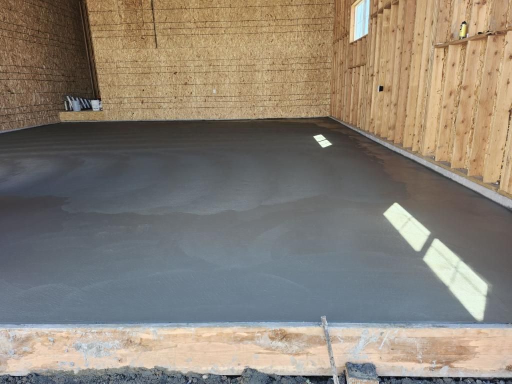A concrete floor in a garage with a wooden wall.