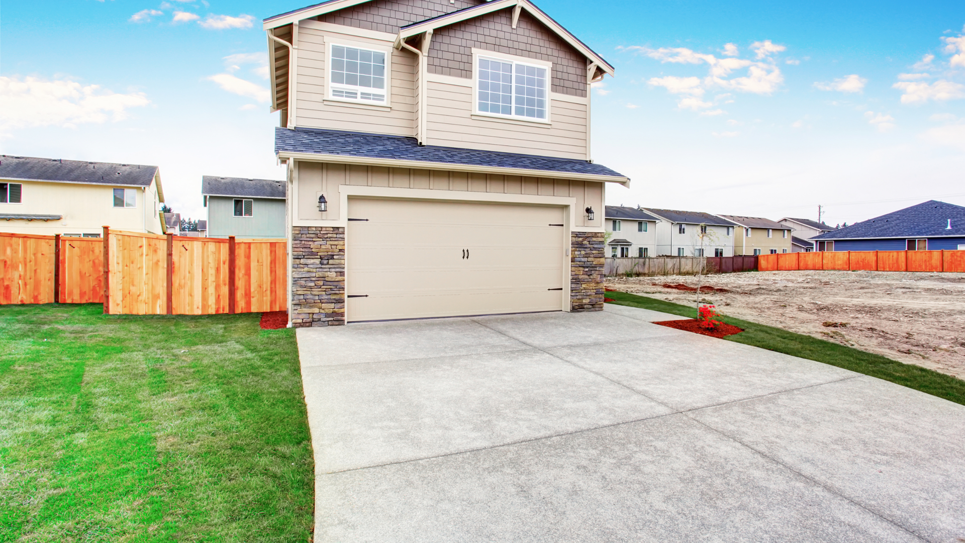 Residential concrete driveway installed in front of a two-story home with clean finish and standard 