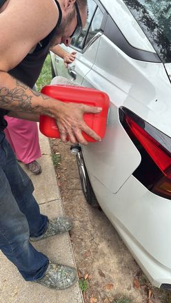 Person working on a car engine, wearing a black watch.
