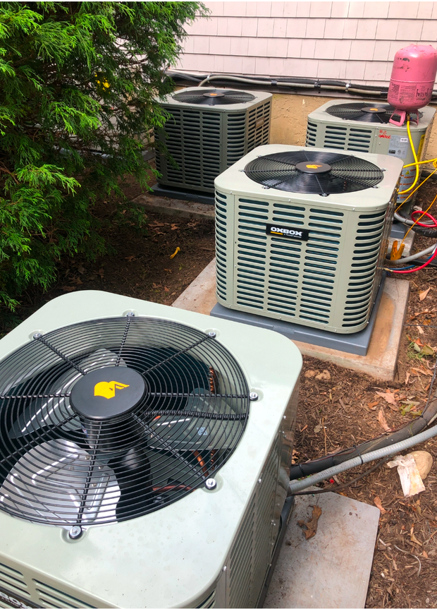 A man is working on an air conditioner on a roof.