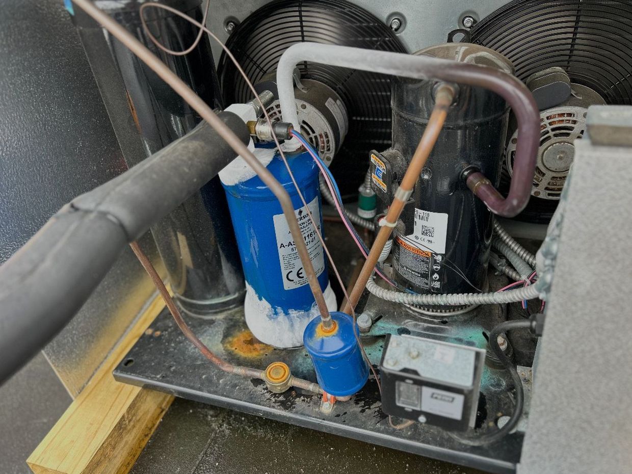 The inside of a machine with a blue cylinder and copper pipes