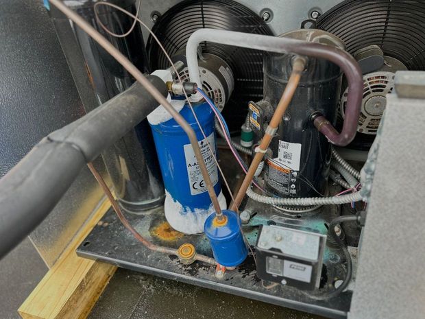 The inside of a machine with a blue cylinder and copper pipes