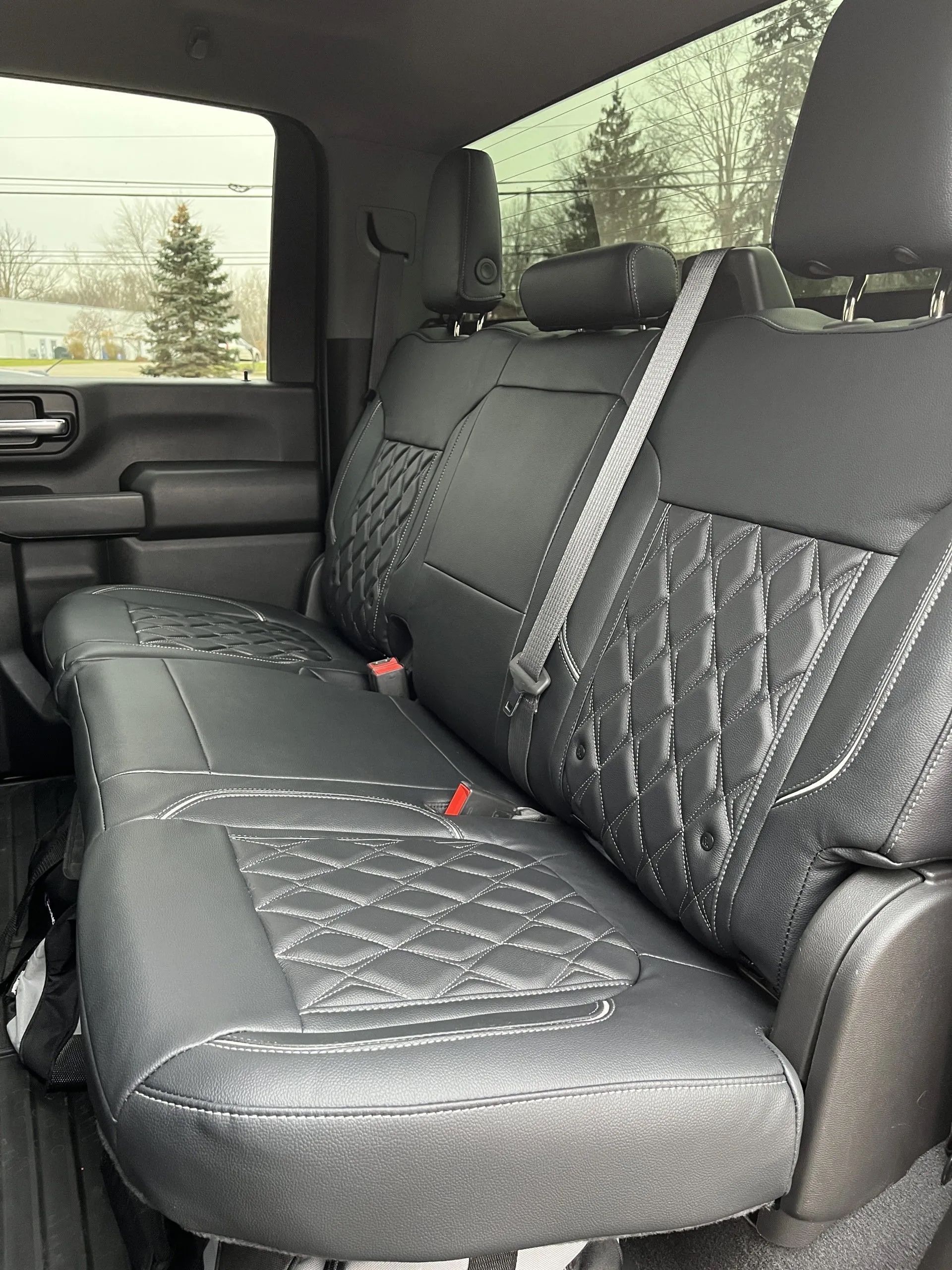 The back seat of a truck with black seat covers and a seat belt