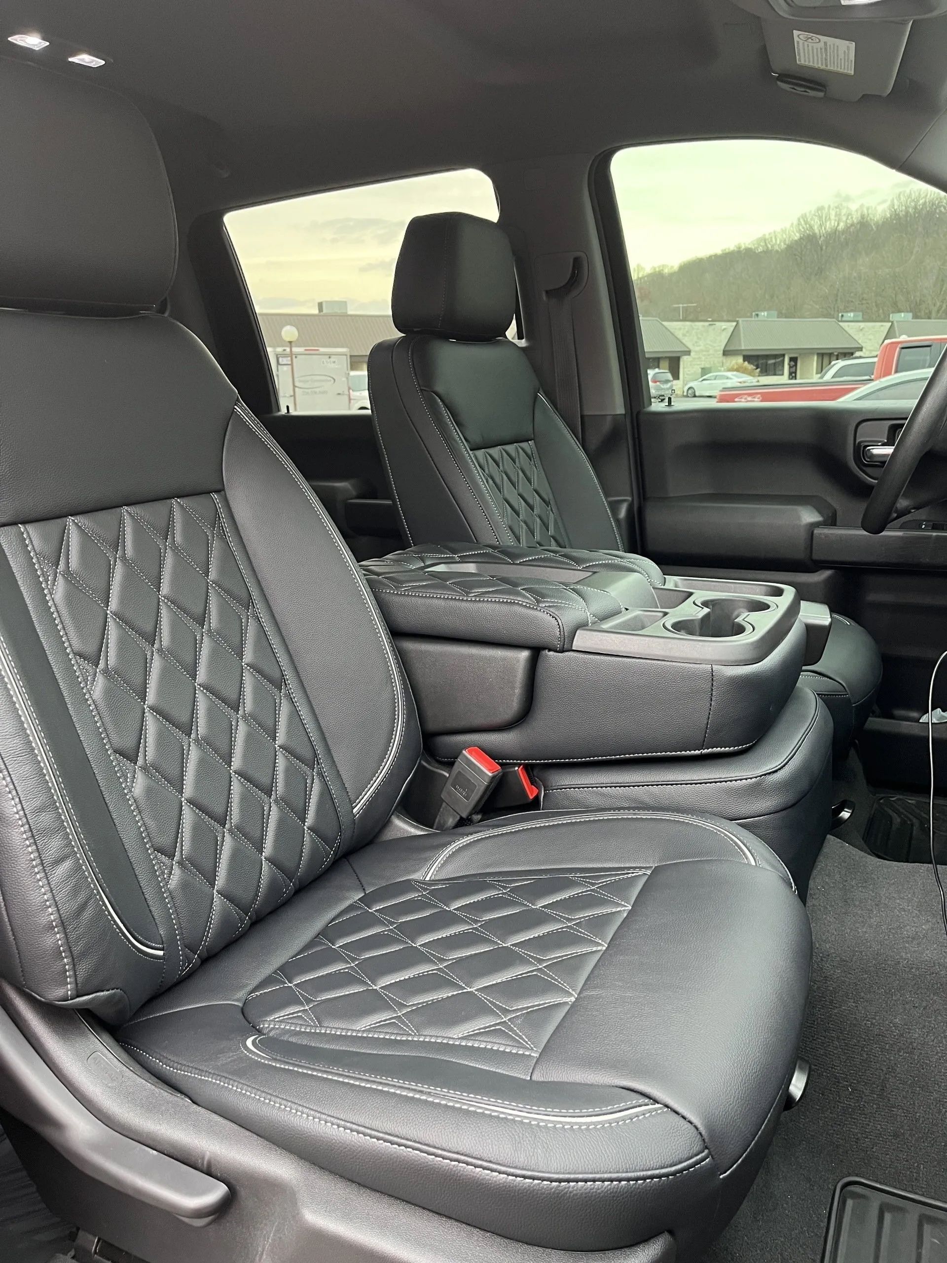 The interior of a truck with black leather seats and a center console