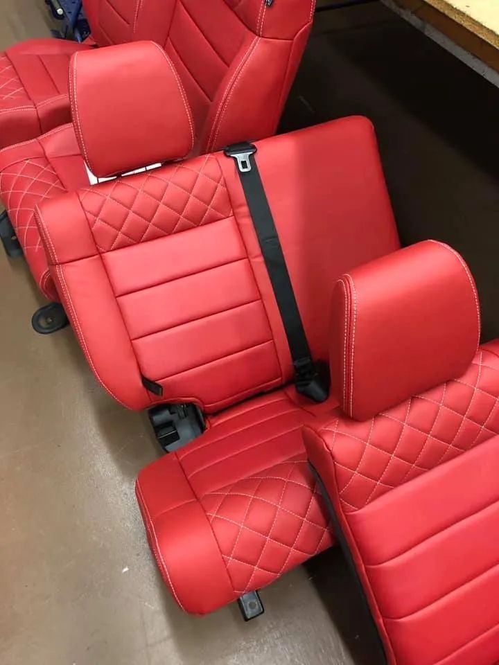 A row of red leather car seats with a black seat belt