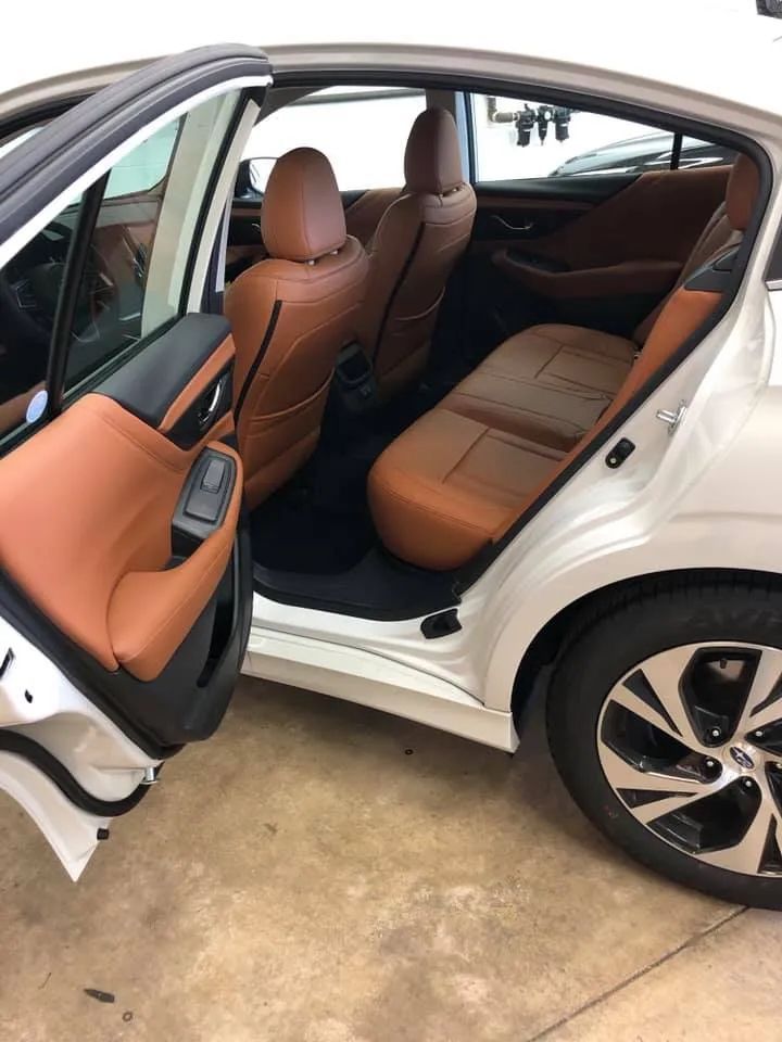 The back seat of a white car with brown leather seats