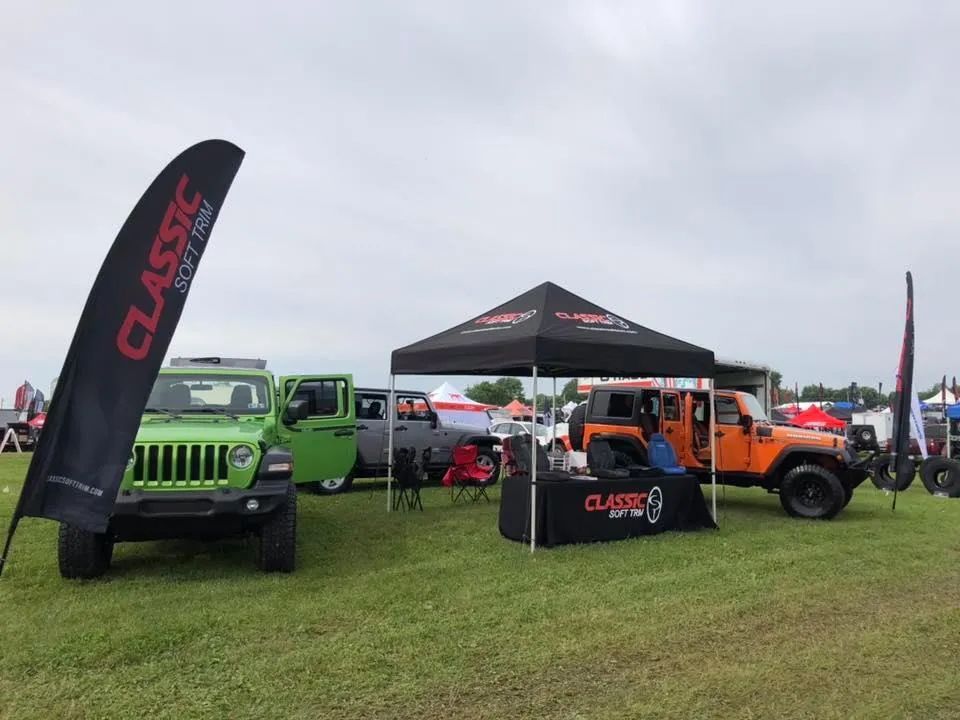 A green jeep is parked next to an orange jeep