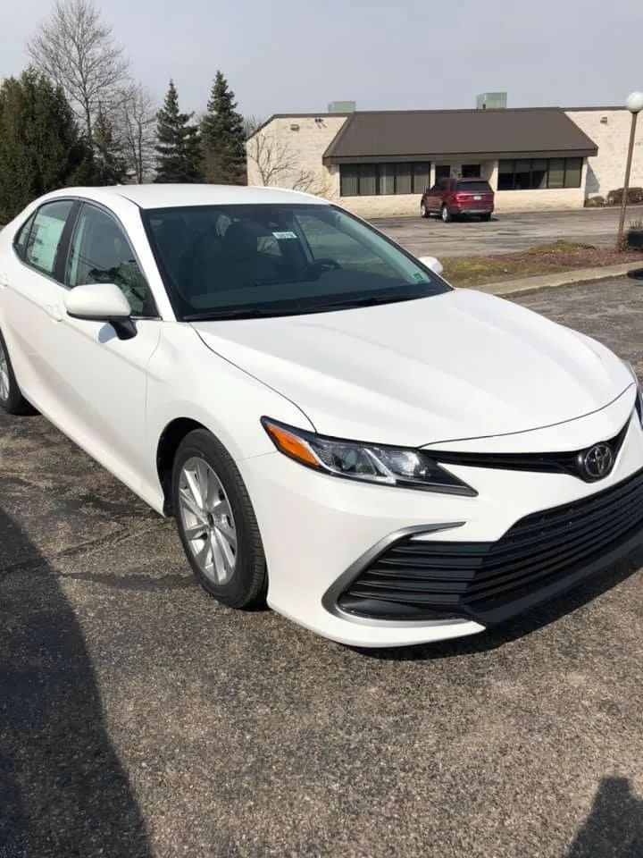 A white toyota camry is parked in a parking lot in front of a building