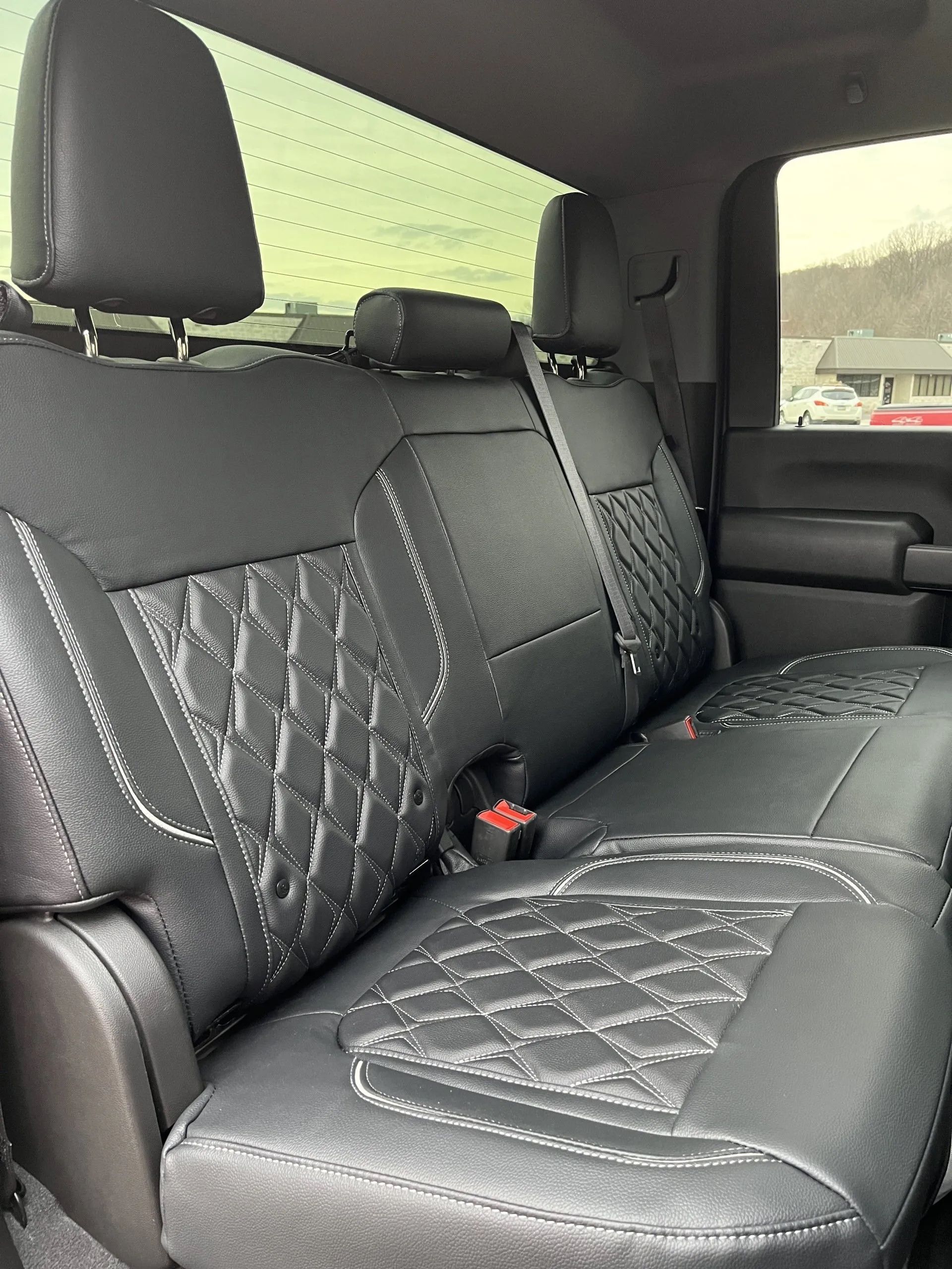 The back seat of a truck with black seat covers
