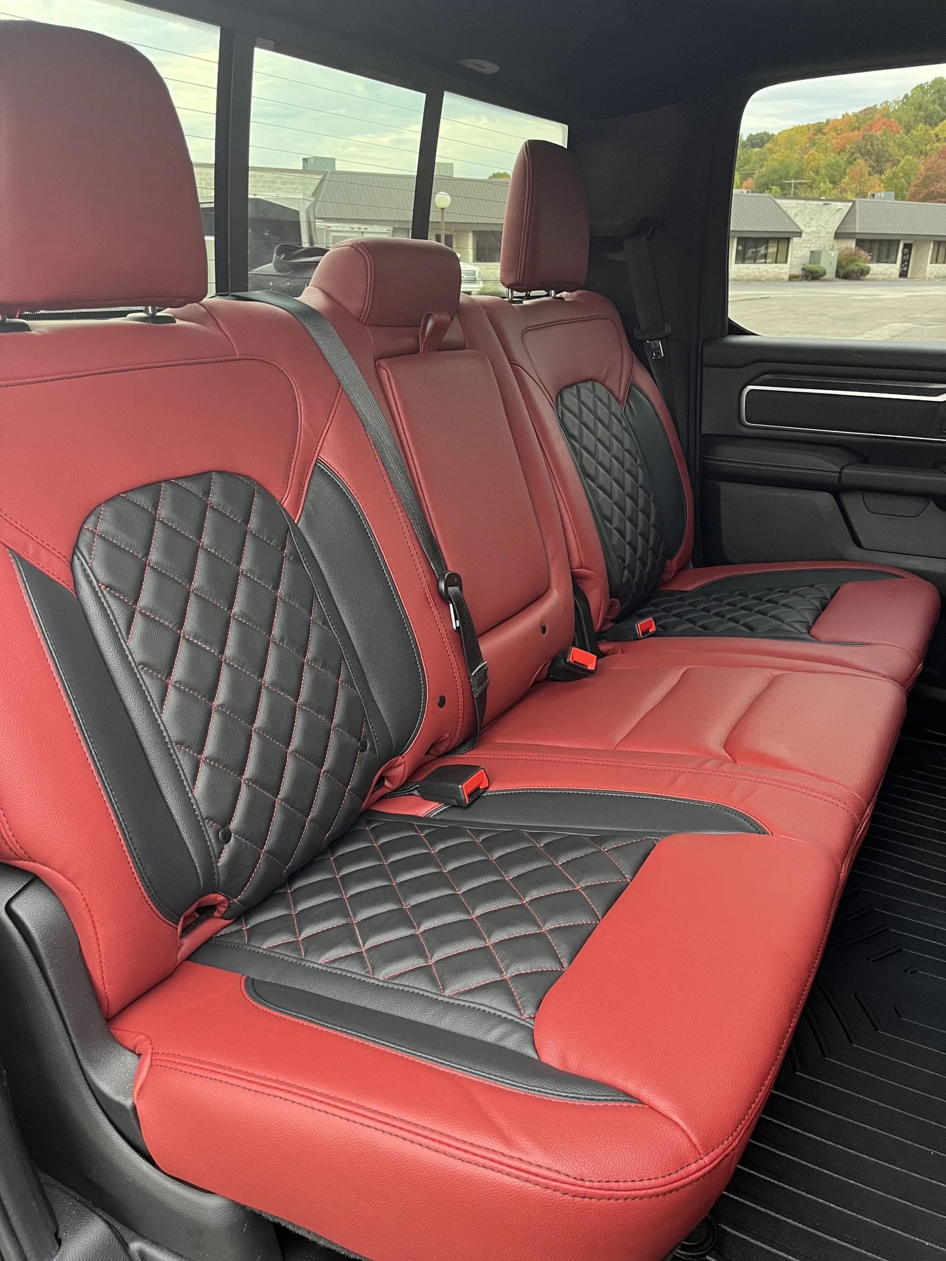 The back seat of a truck with red and black seat covers
