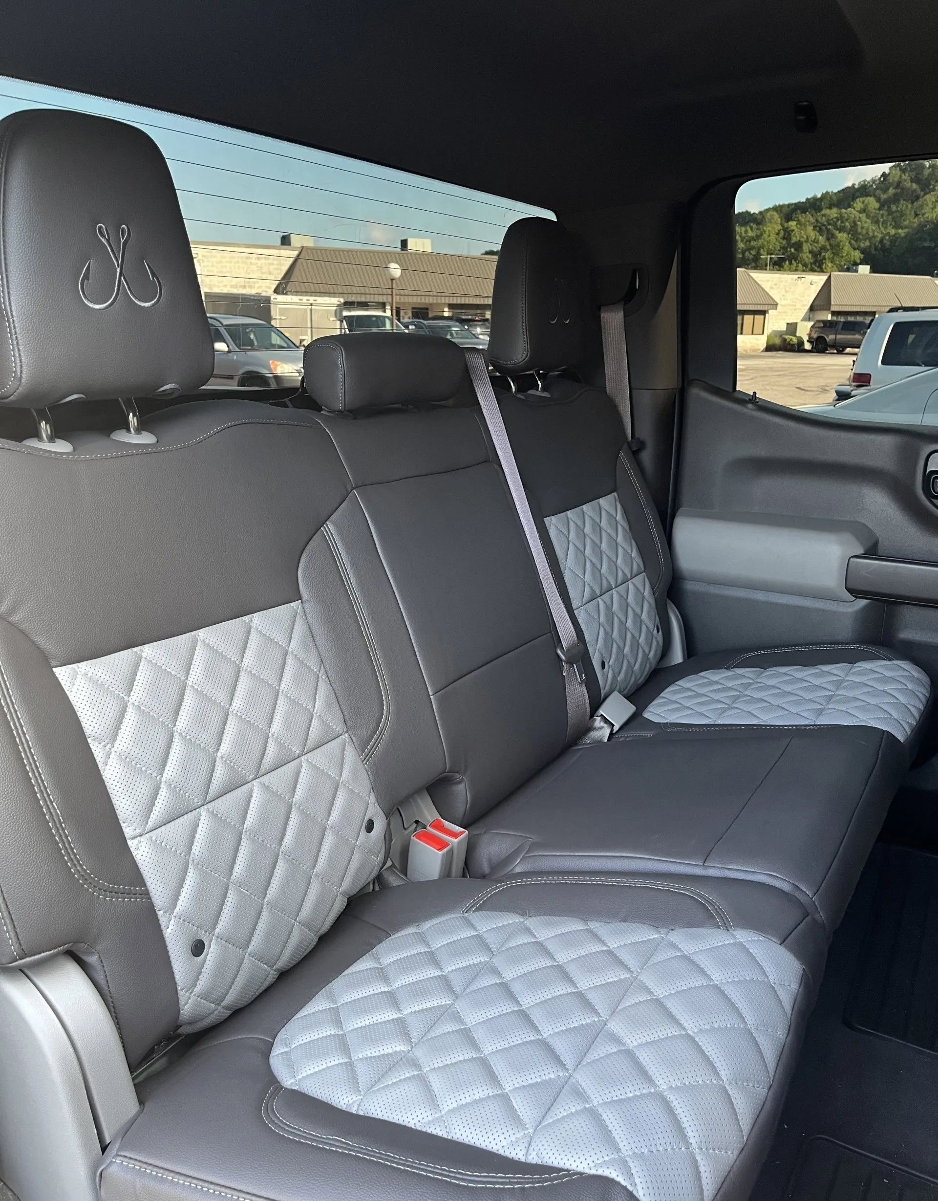 The back seat of a truck with gray and white seat covers