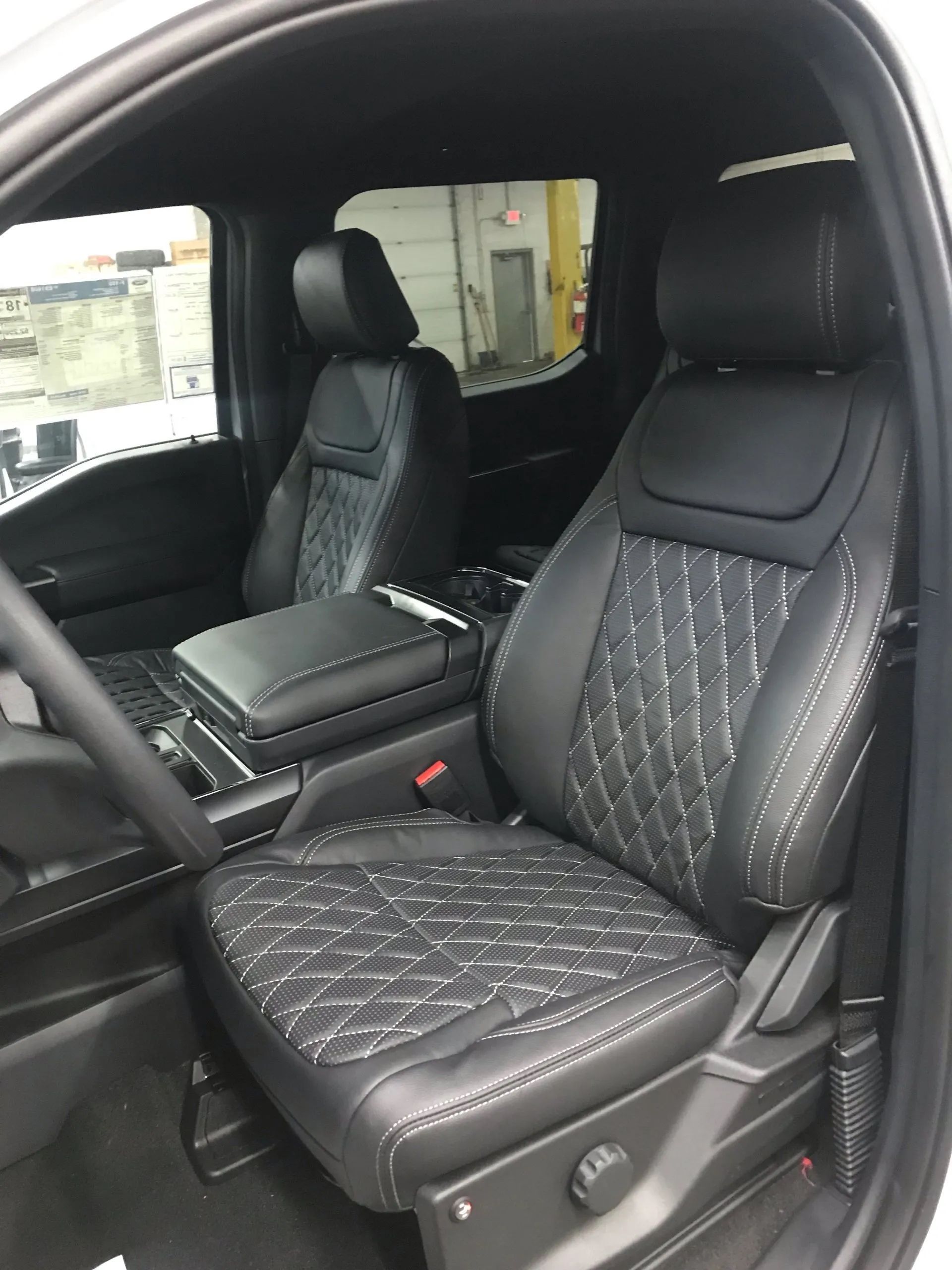 The interior of a white truck with black seats and a steering wheel