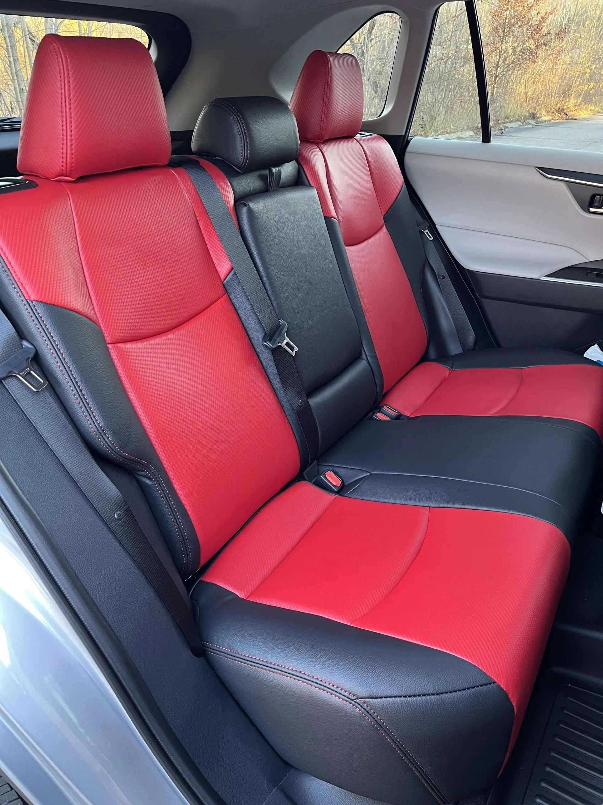 The back seat of a car with red and black seats