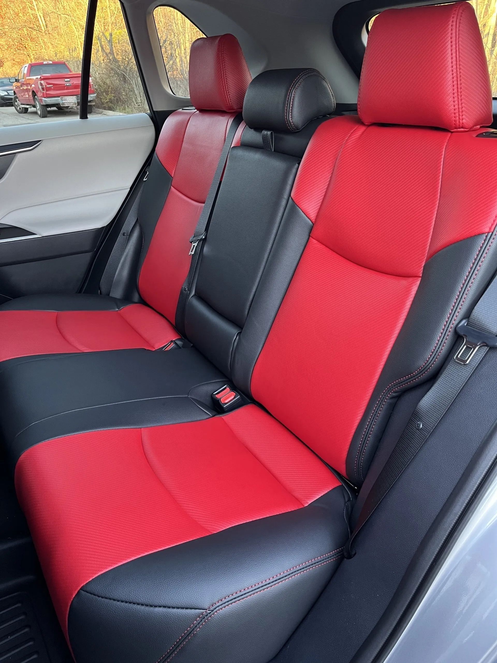 The back seat of a car with red and black seat covers