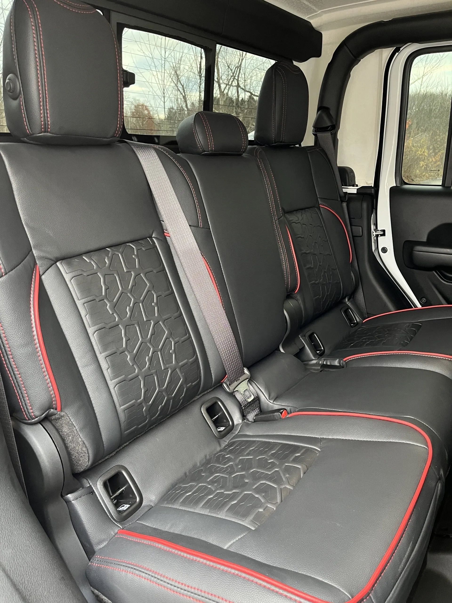 The back seat of a jeep wrangler with black leather seats and red trim